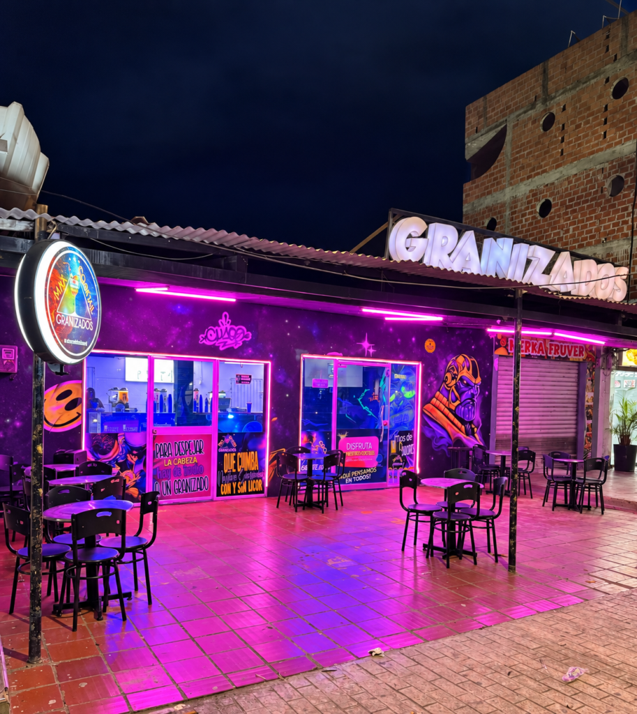 Fachada de Max Cocktail La Jagua de Ibirico con aviso de Granizados, mesas exteriores e iluminación neón.