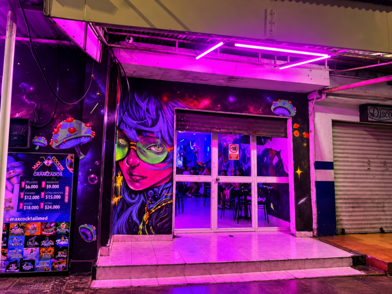 Acceso al local de Max Cocktail Las Peñitas en Sincelejo, con mural de colores y puertas de vidrio.