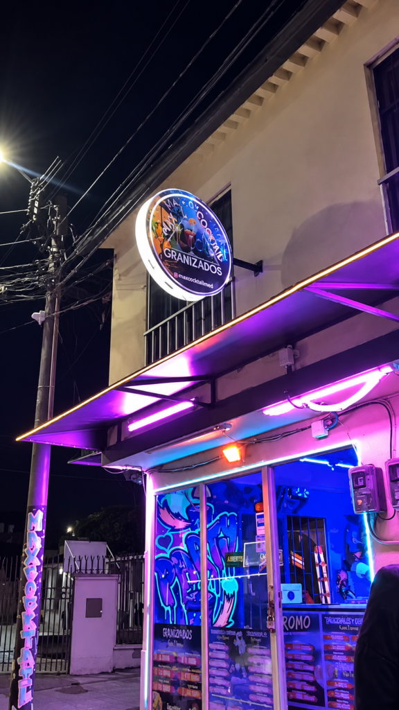 Fachada de Max Cocktail Villamaría, con aviso circular e iluminación neón.