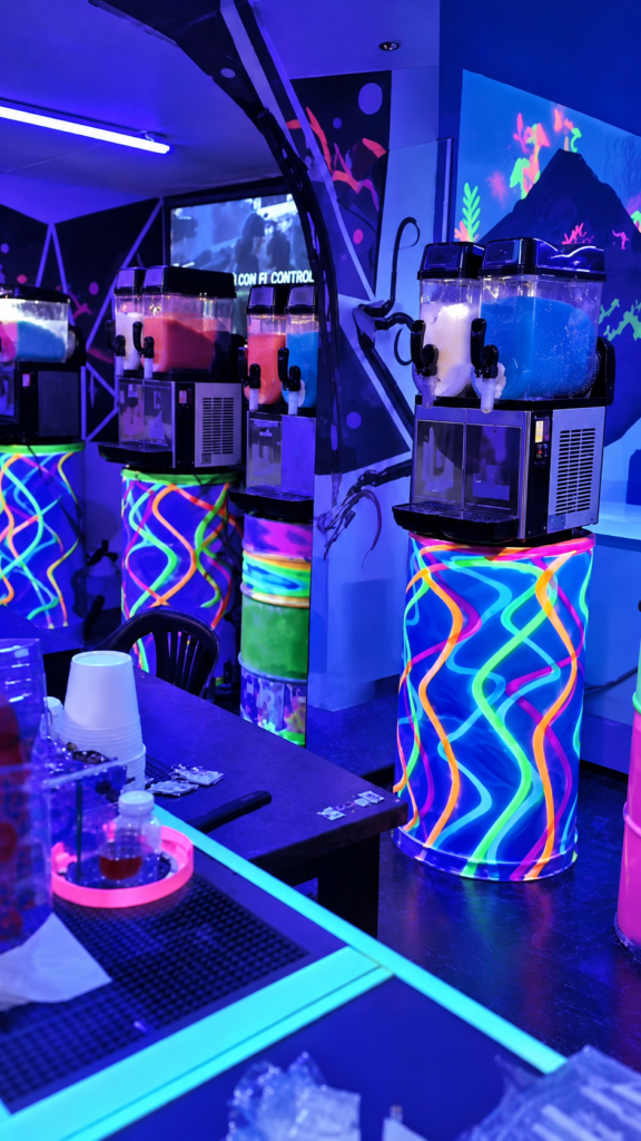 Interior de Max Cocktail Villamaría, con máquinas de granizados y decoración neón.